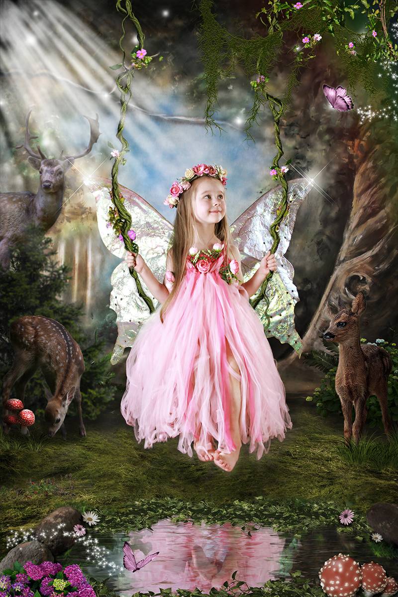 Little girl fairy on swing by a pond in a magical, enchanted forest